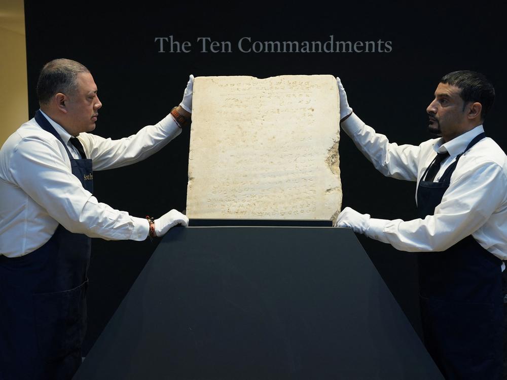 Sotheby's workers hold the stone tablet of the Ten Commandments that is scheduled for auction.