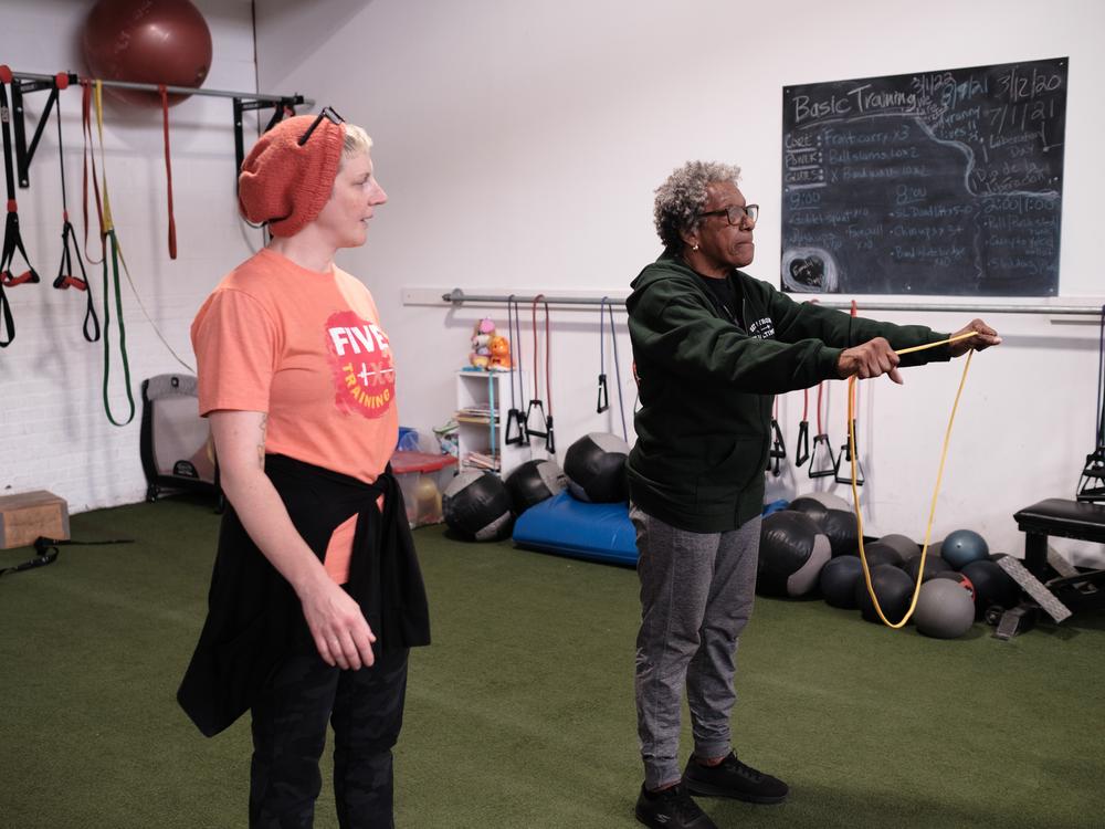Owner and trainer Emily Socolinsky assists Victoria Howard, 75, through a workout.