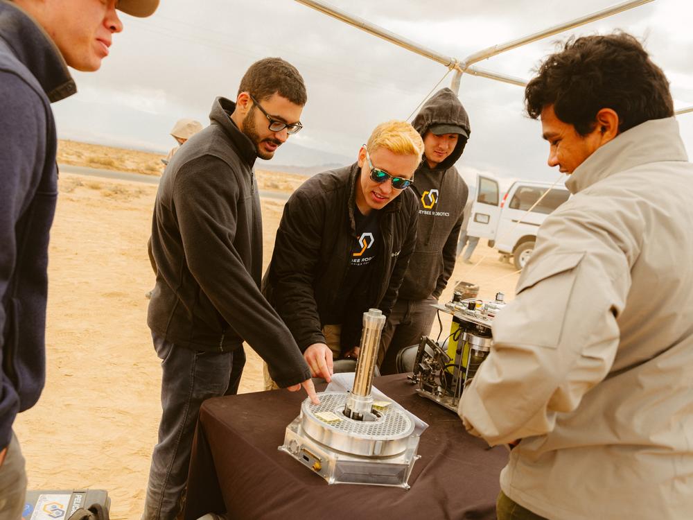Representatives from Honeybee Robotics show off robot components.