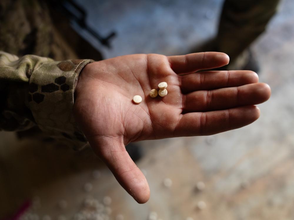 A soldier with the HTS shows some of the Captagon pills that they found at the facility.