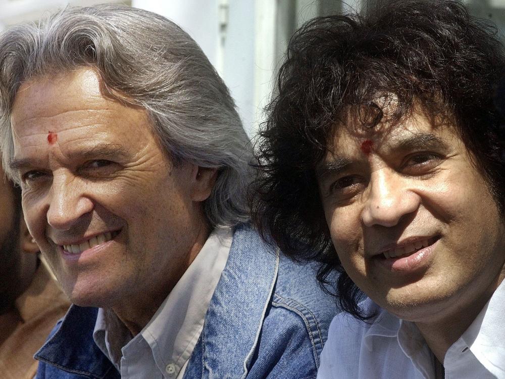 Guitarist John McLaughlin (L) and tabla maestro Zakir Hussain listen to a journalist's question upon arrival at their hotel in Bangalore, India, on Jan. 30, 2003.