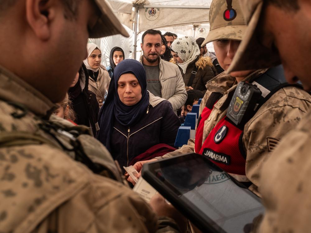 Turkish gendarmerie check the documents of Syrian families living in Turkey at the Cilvegozu border gate as they wait to cross into Syria, on Dec. 13, after Syrian rebels ousted President Bashar al-Assad.