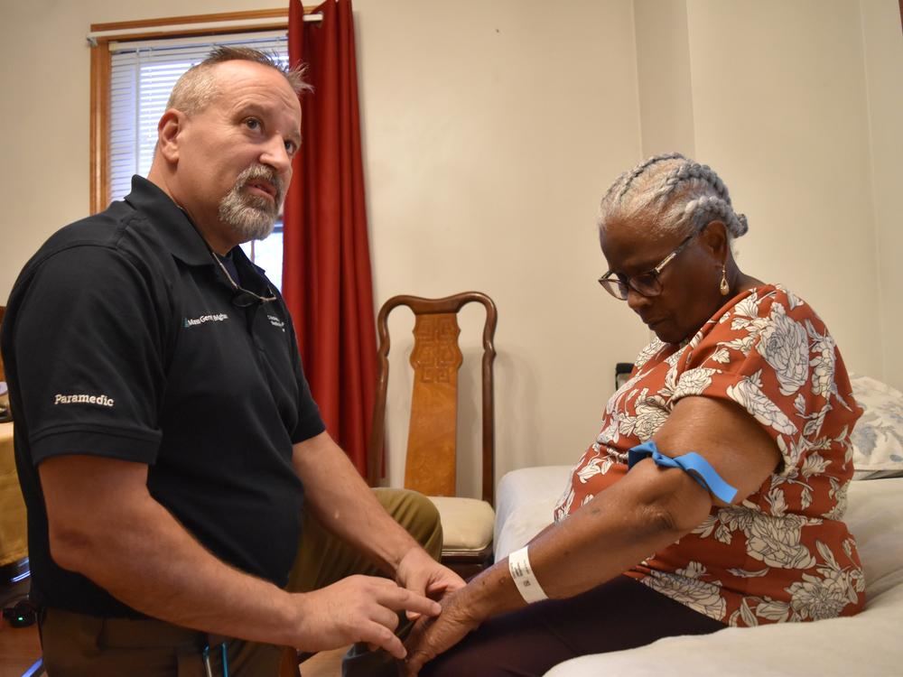 Shane McMahon, a paramedic, checks on Stephanie Joseph, 91, who received care through Mass General Brigham's hospital-at-home program.