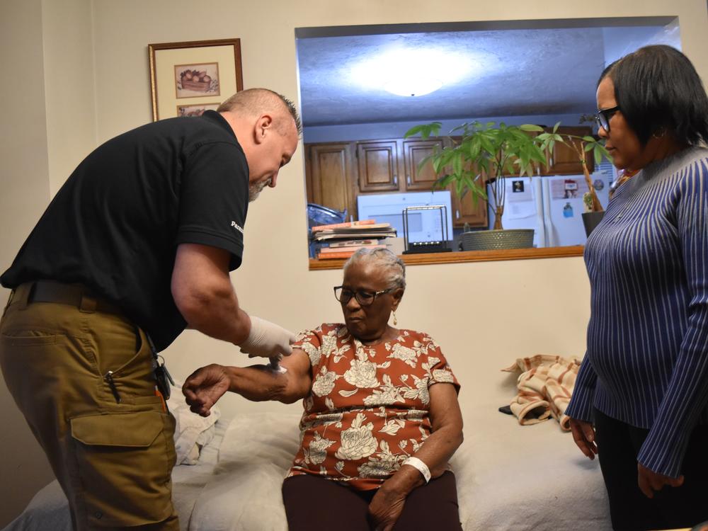 The Medicare and Medicaid waiver that makes the hospital-at-home program possible expires on Dec. 31, 2024. Congress could extend it. Stephanie Joseph's daughter, Ketline Edouard, helps paramedic Shane McMahon care for her mom.