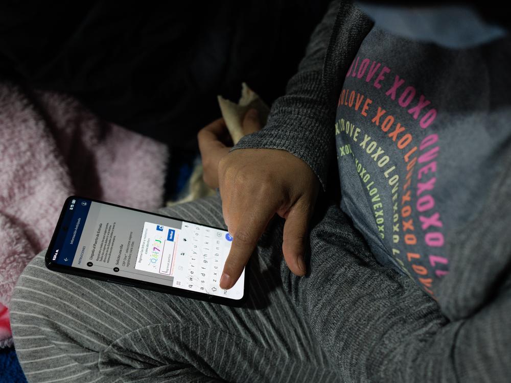 Venezuelan Bárbara Mendoza, 28, logs into the CBP One application atop her bunk in El Buen Samaritano migrant shelter in Ciudad Juárez, Chihuahua state, Mexico on Monday, December 9, 2024.