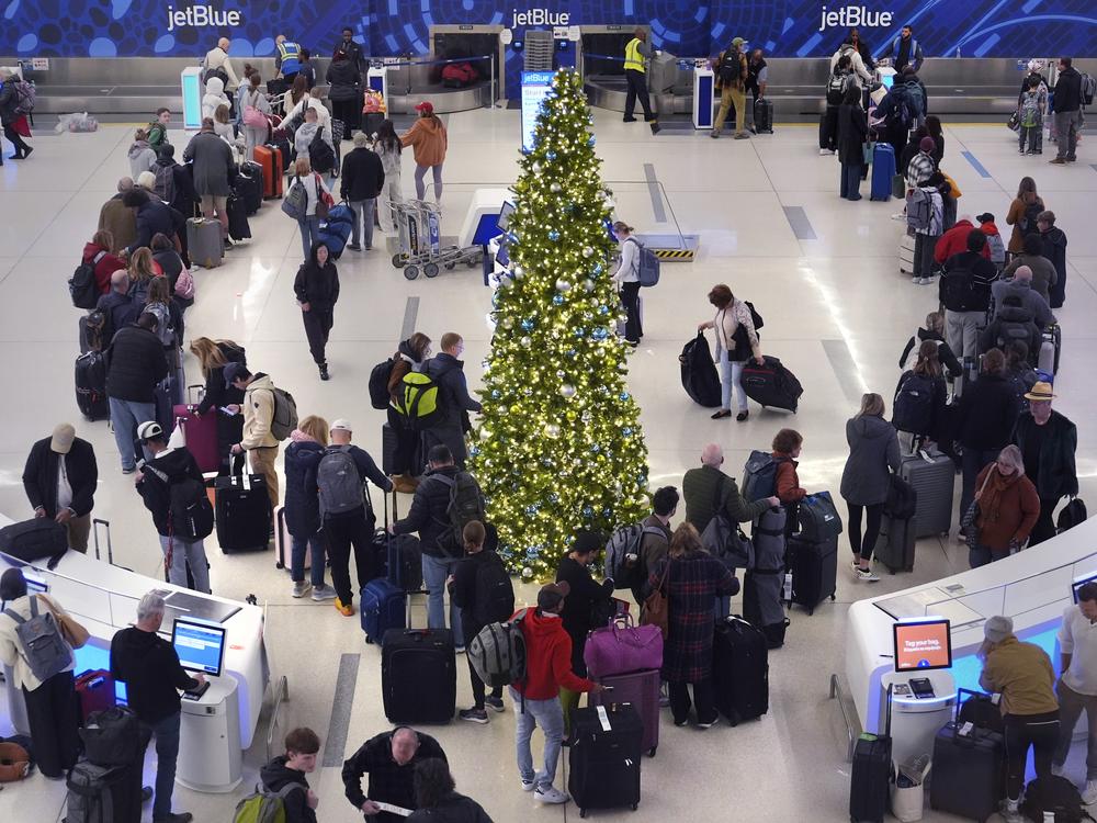 Holiday travelers wait in line to check their bags at the JetBlue terminal at Boston's Logan Airport on Friday.