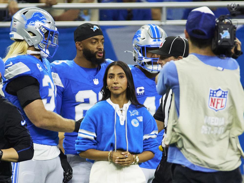 Detroit Lions linebacker Alex Anzalone (34) and Honorary captain Diana Flores, Flag Football Ambassador, on the sideline before the game against the Tampa Bay Buccaneers on Sept. 15, 2024.