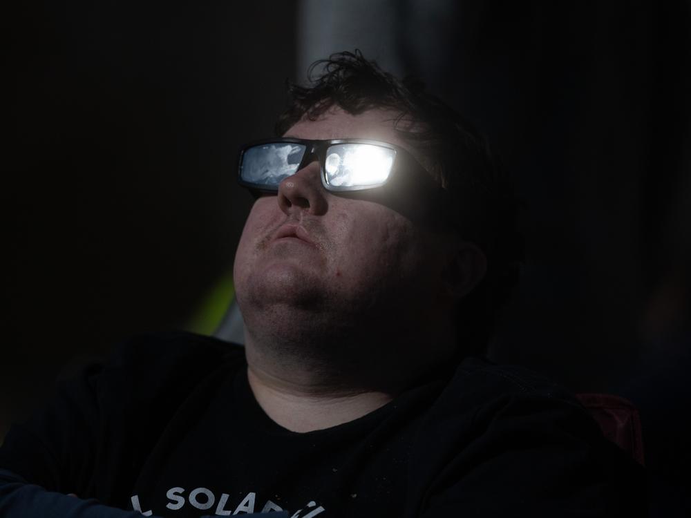 The sun catches the solar glasses of a man watching the Great North American Eclipse on April 8 in Colebrook, N.H.