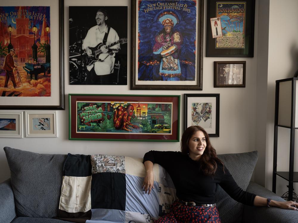 Amanda Kastrinos at her apartment in New York City, decorated with concert and festival posters, as well as a black-and-white photo of her dad playing guitar. 