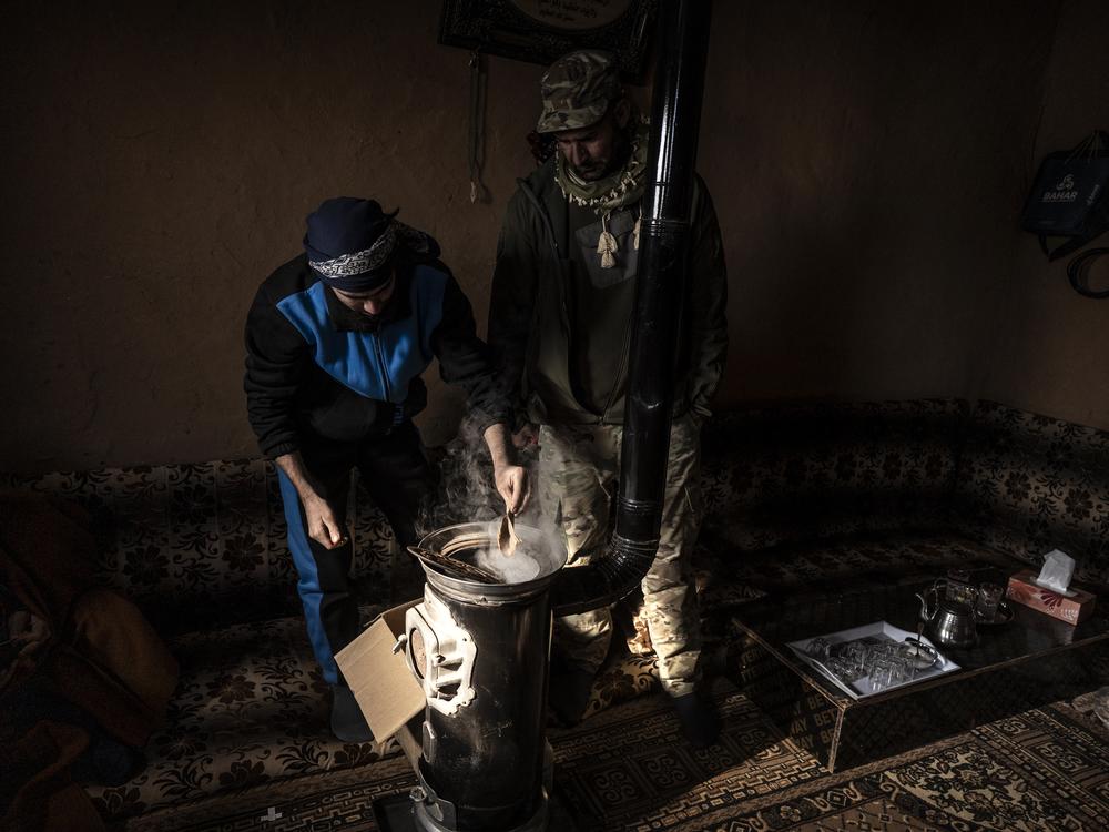Displaced Syrians, one a member of the U.S.-backed Syrian Free Army, light the stove in one of one of hundreds of mud-brick houses that make up the Rukban camp, Dec. 14.