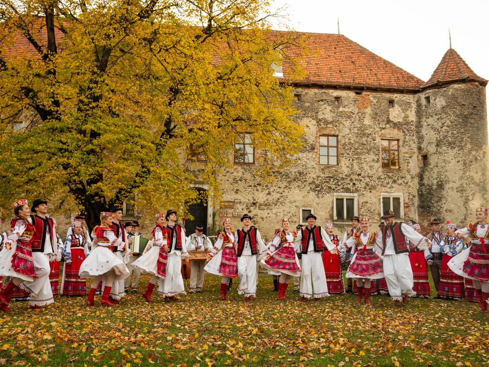 The Transcarpathian Folk Choir performs a song and dance for a music video that they are working on to share their music. Ukraine's St. Miklos Castle, which is now an arts exhibit space, a meeting place and museum for local history, provides the backdrop.