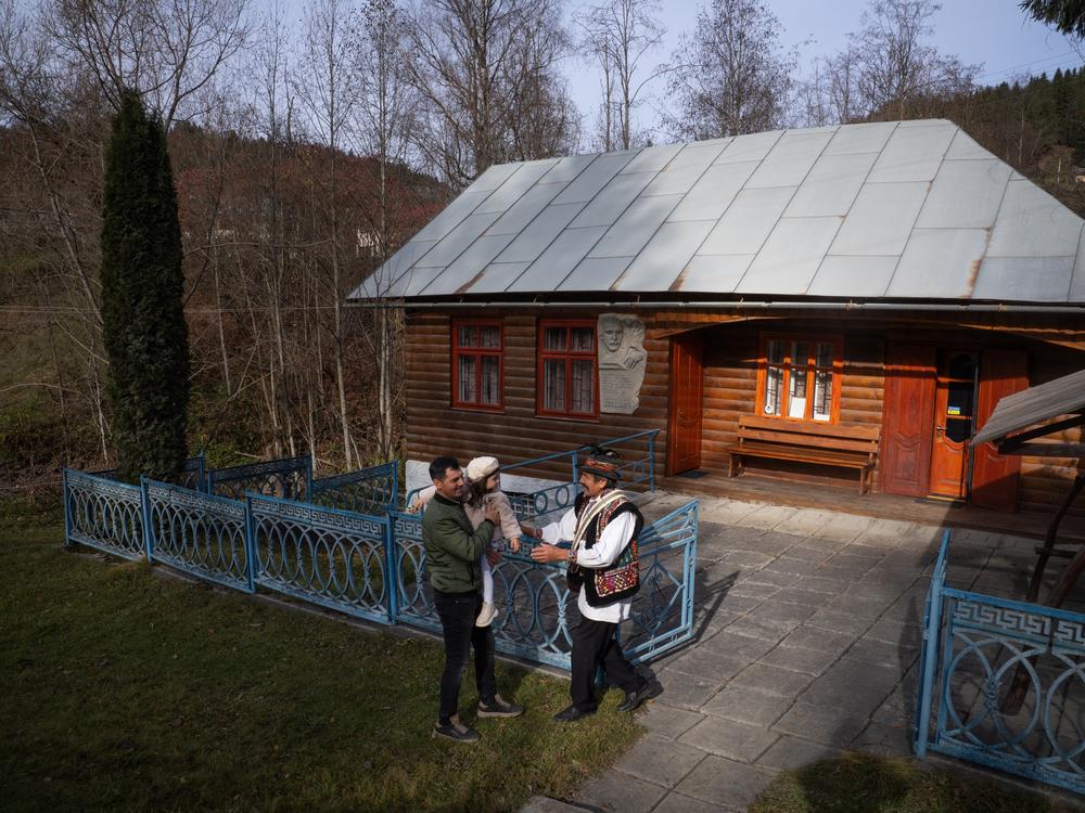 Volodymyr Sinitovych, director of the Hutsul Theater, greets his son and grandchild outside the small museum in Krasnoillya, where the history of Hutsul theater is documented and sometimes performed.