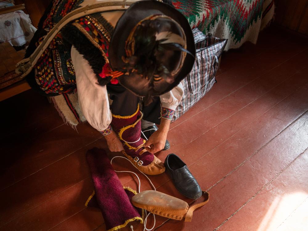 Volodymyr Sinitovych ties up traditional shoes that are part of his costume.