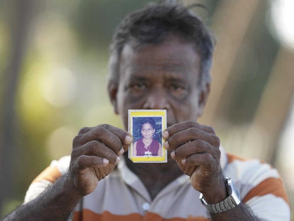 Dayaratne Halambage shows a portrait of his daughter, who died during the tsunami, at a memorial of the 20th anniversary of the calamity in Peraliya, Sri Lanka, on Thursday.