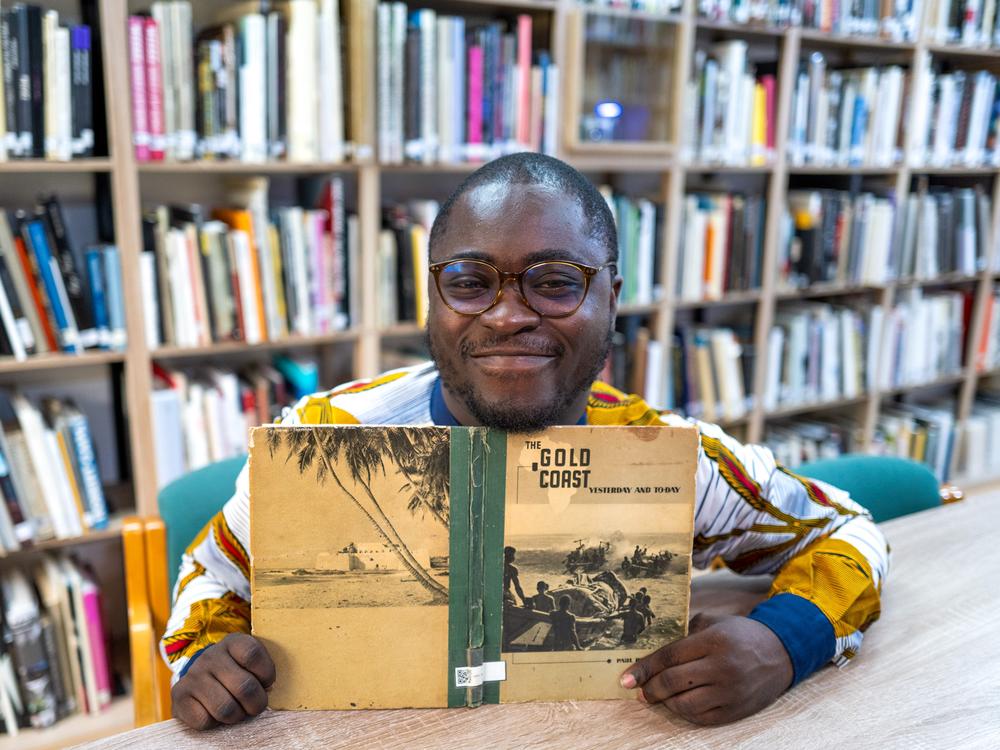 Paul Ninson of Ghana embraced photography as a career -- and was inspired to create a library of photobooks about Africa. Above: Ninson in the Dikan Center in the capital city of Accra, which marked its second anniversary this month. He's holding a copy of the center's oldest book, <em>The Gold Coast Yesterday and Today,</em> published in the early 1940s.