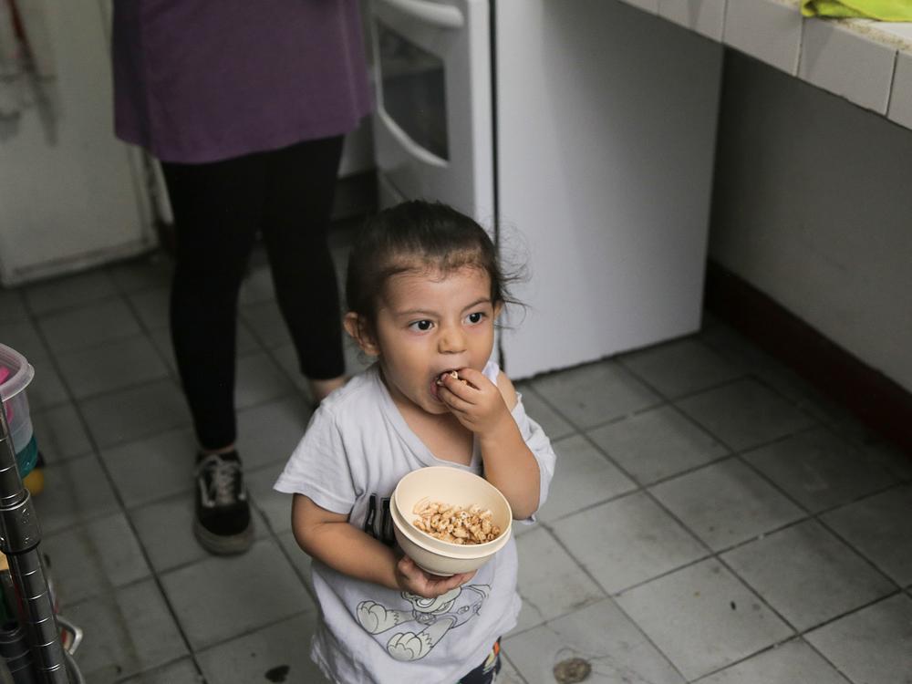Tomás, who is 2, snacks on puffed rice cereal while his parents cook a meal.