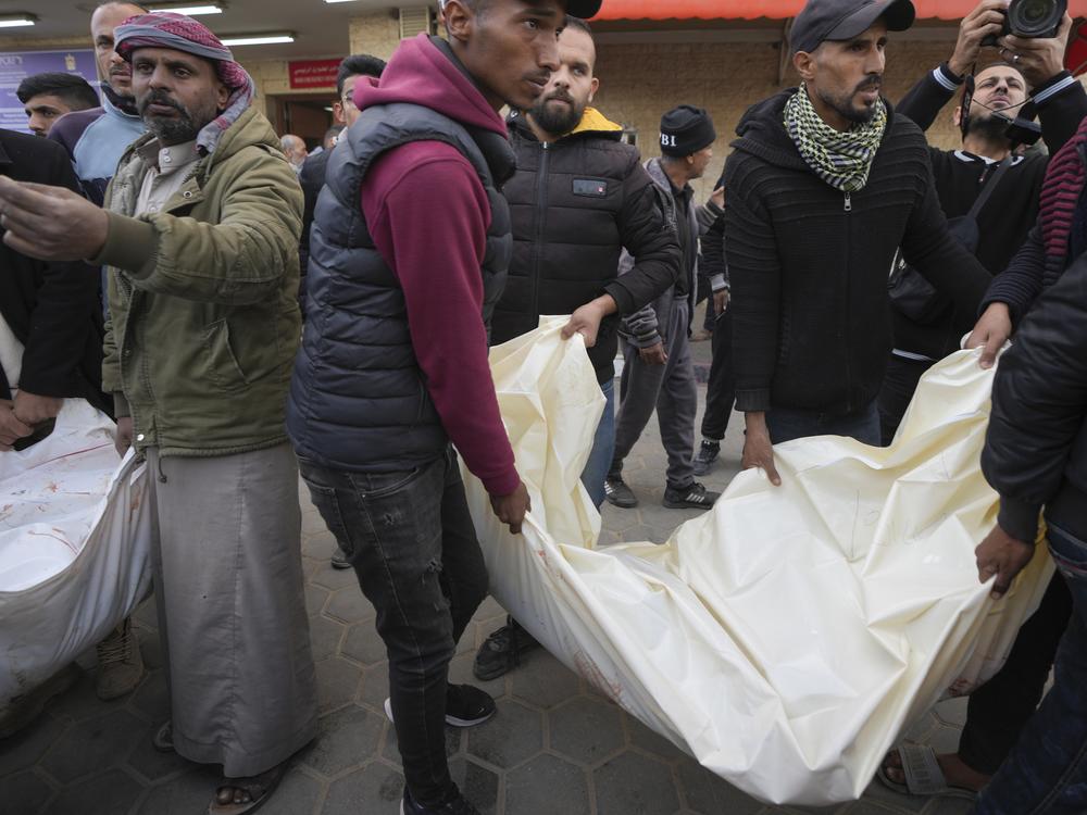 Palestinians carry white sacks containing the bodies of those killed in overnight Israeli airstrikes on the Maghazi refugee camp, at Al-Aqsa Hospital, in Deir al-Balah, central Gaza Strip, on Saturday.