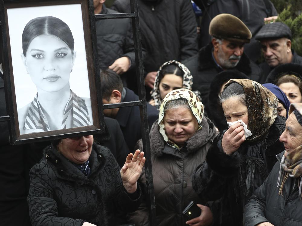 People mourn at the grave of flight attendant Hokume Aliyeva during a funeral of the crew members of the Azerbaijan Airlines Embraer 190 killed in a deadly plane crash in Kazakhstan this week, at the II Alley of Honor in Baku, Azerbaijan, Sunday, Dec. 29, 2024.