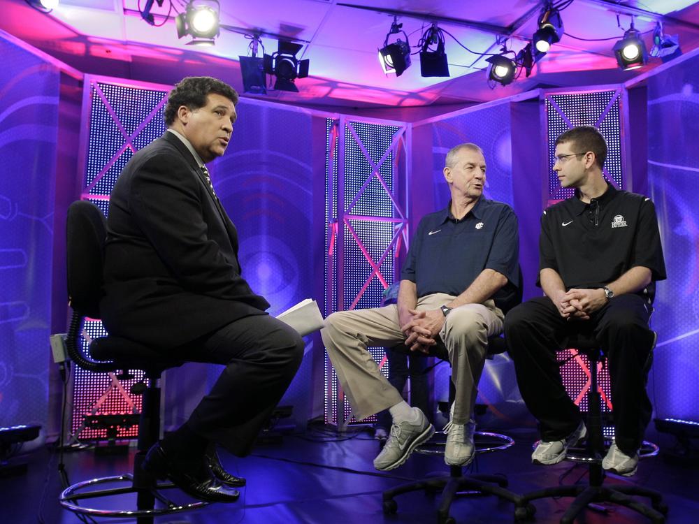 FILE - Greg Gumbel, left, watches as Connecticut head coach Jim Calhoun talks to Butler head coach Brad Stevens, right, prior to taping a television interview for the men's NCAA Final Four college basketball championship game on April 3, 2011, in Houston.