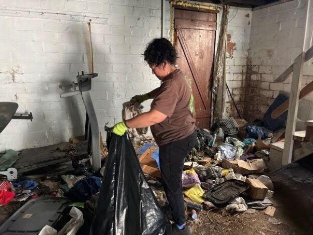 Eva Williams, wife of Fight the Blight founder Matt Williams, works to clean the basement of someone with hoarding disorder. The homeowner decided to clear out their home in Youngwood, Pennsylvania, after attending Fight the Blight's course and support group.<br>