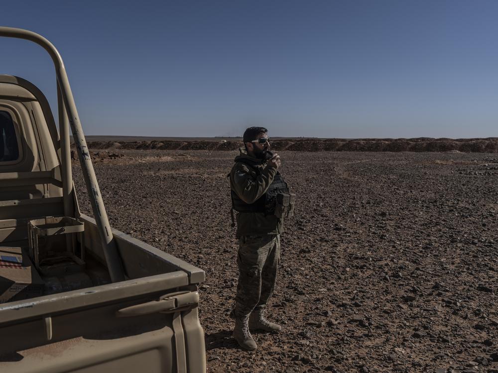 A Syrian Free Army fighter stands a few hundred yards from a sand berm marking the border between Jordan and Syria on the outskirts of Rukban camp in southern Syria, Dec. 14.<br><br>