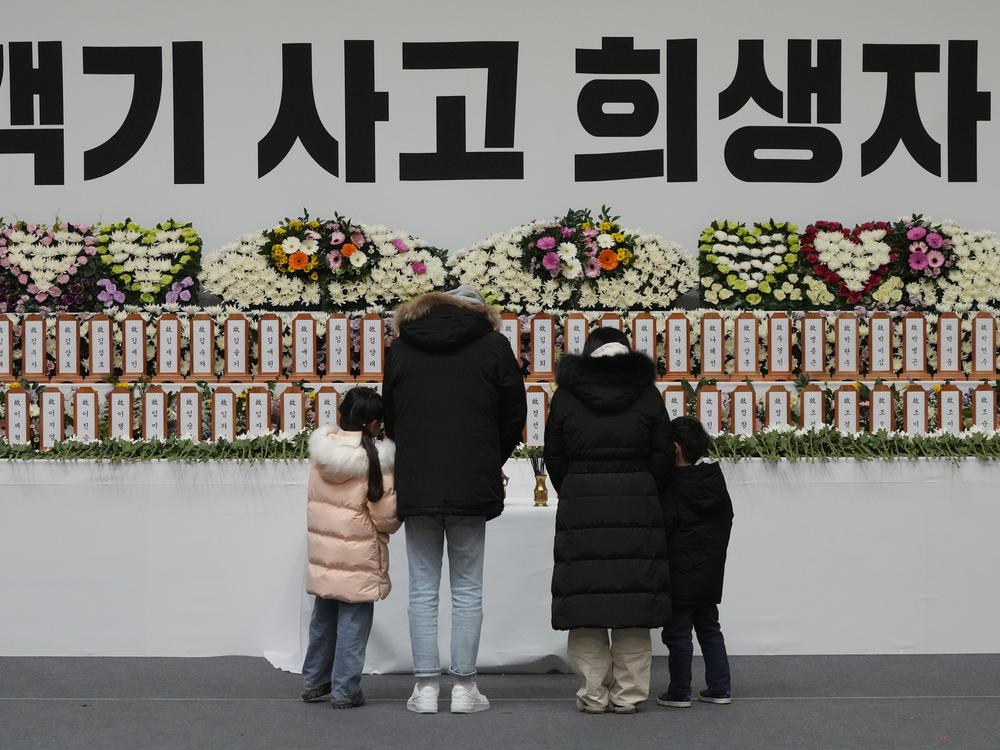 Mourners pray for the victims on a plane fire at a memorial altar at Muan sport park in Muan, South Korea on Monday. The sign reads 