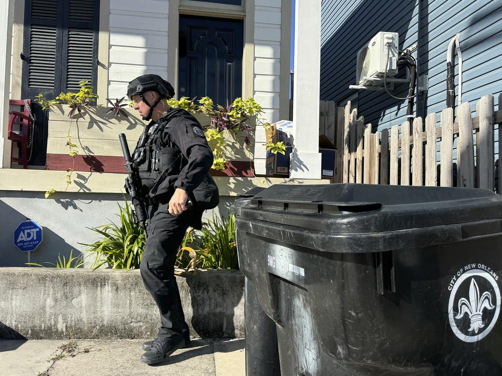 A New Orleans police officer searches the area near a crime scene after a vehicle drove into a crowd on Canal and Bourbon Street.
