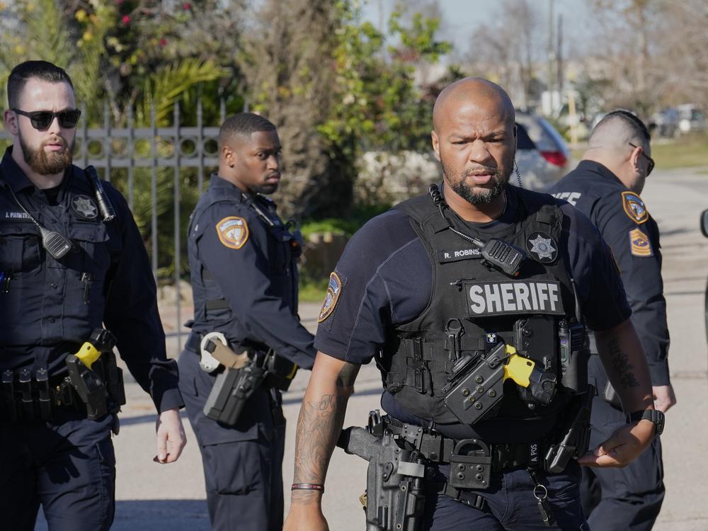 Harris County Sheriff's officers clear the media from the neighborhood where the suspect is believed to have lived.
