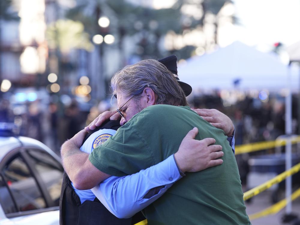 Edward Bruski, right, hugs New Orleans police officer Zachary Stevenson at the scene where a vehicle drove into a crowd on New Orleans' Canal and Bourbon Street.