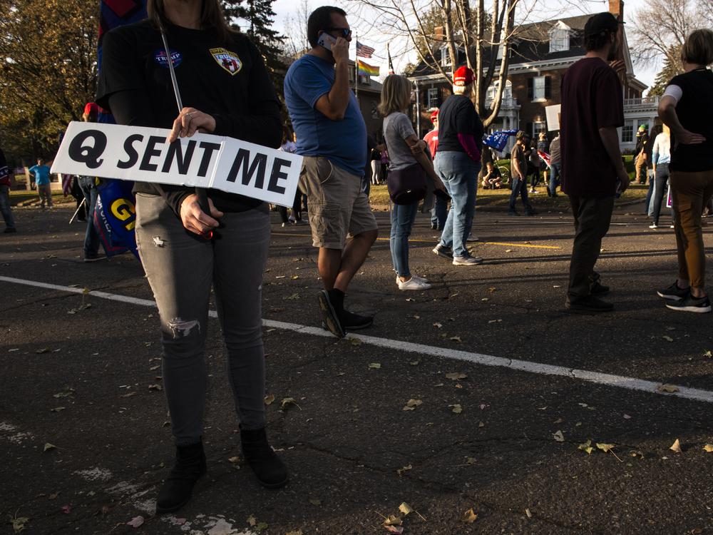 A woman holds a sign referencing the QAnon conspiracy on Nov. 7, 2020 in St. Paul, Minn. QAnon emerged online in 2017 and claims that Trump is involved in a secret battle against evil members of the alleged deep state, or in other tellings, a powerful cabal of government and Hollywood elites engaged in satanic child abuse.