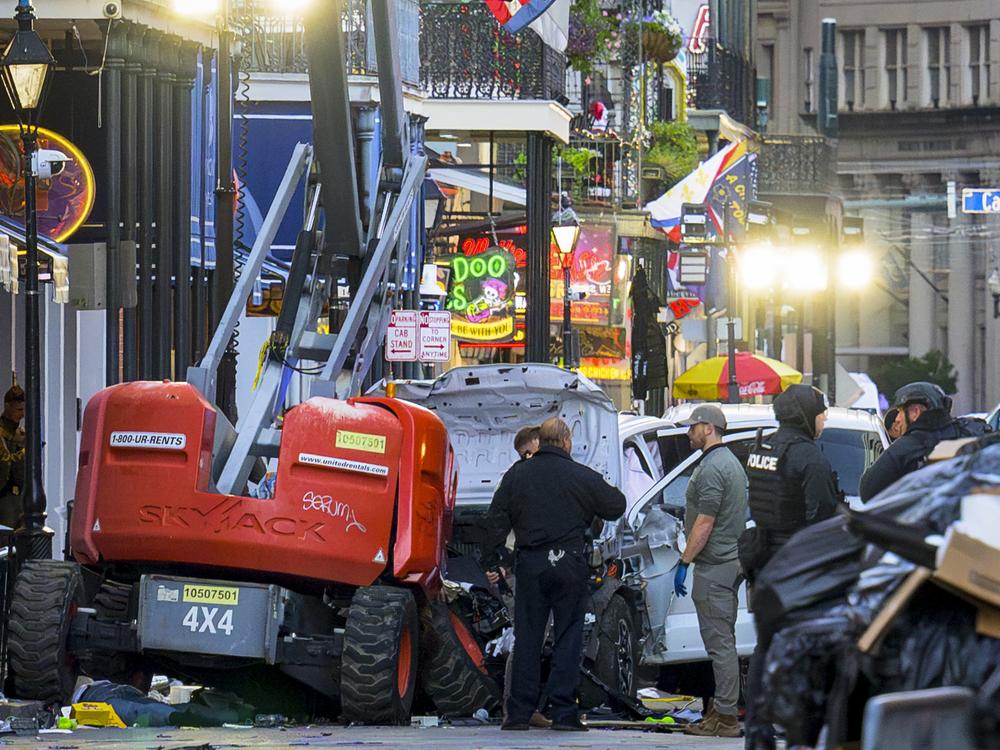 Police investigators surround the white Ford F-150 pickup truck that crashed into a work lift after allegedly driving into a crowd of New Year's revelers in the French Quarter of New Orleans.