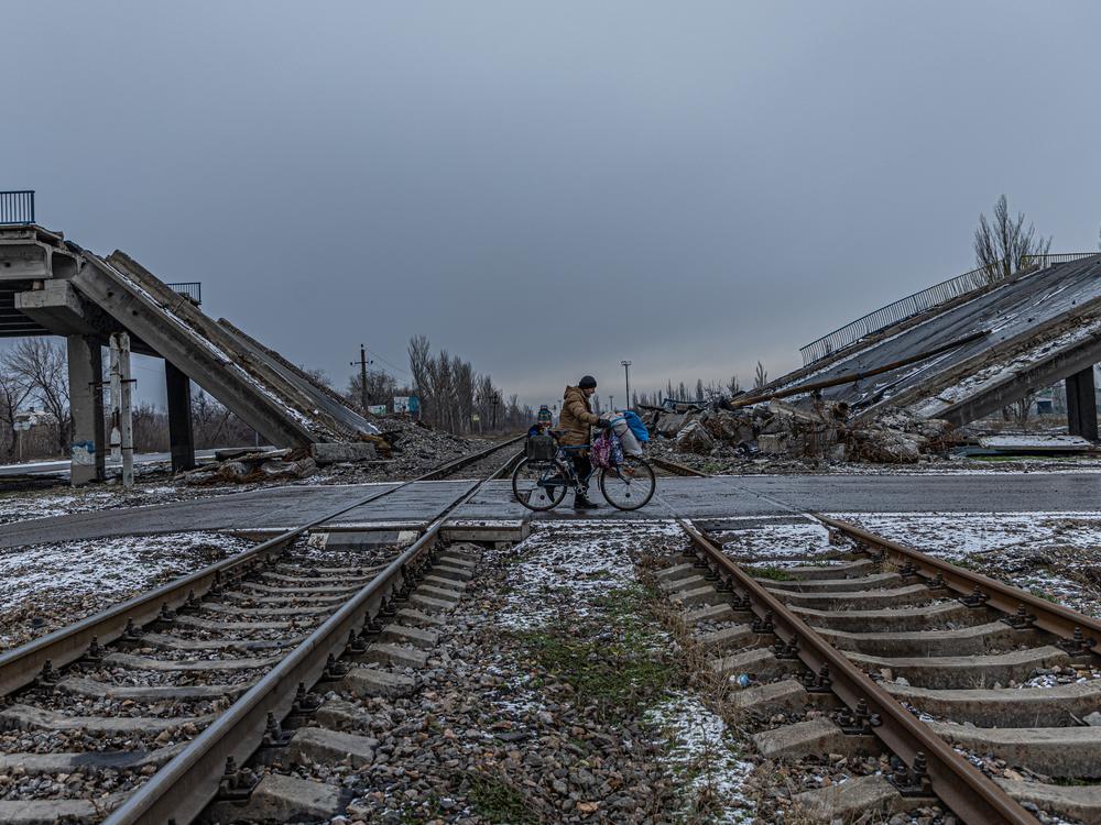 A man carries his belongings on a bicycle past a bridge destroyed by Russian shelling on the eastern outskirts of Pokrovsk.  Local military officials say much of the city's infrastructure has been ruined by rockets, artillery and drone strikes.