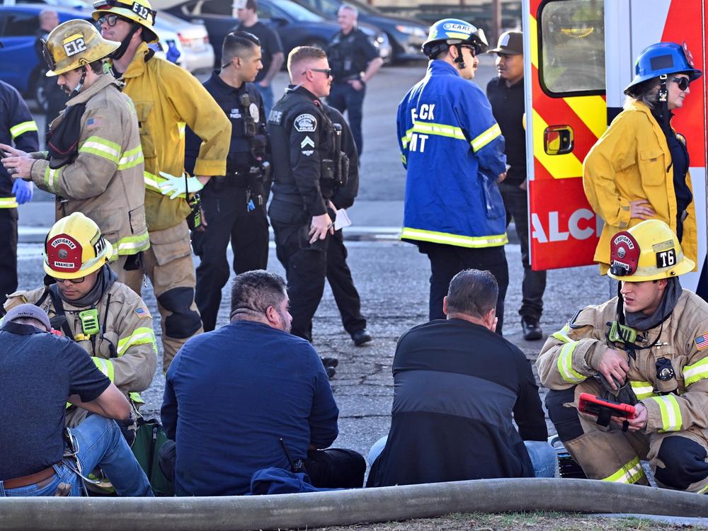 Firefighters tend to people after a plane crashed through the roof of a building near Fullerton airport on Jan. 2, 2025, in Fullerton, Calif.