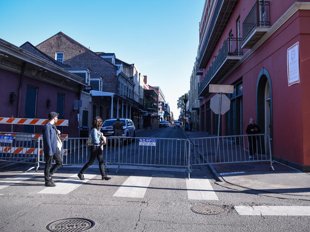 Two people walk by a New Orleans Police barricade still in place on Bourbon Street. The street is currently open only to foot traffic. ⁠