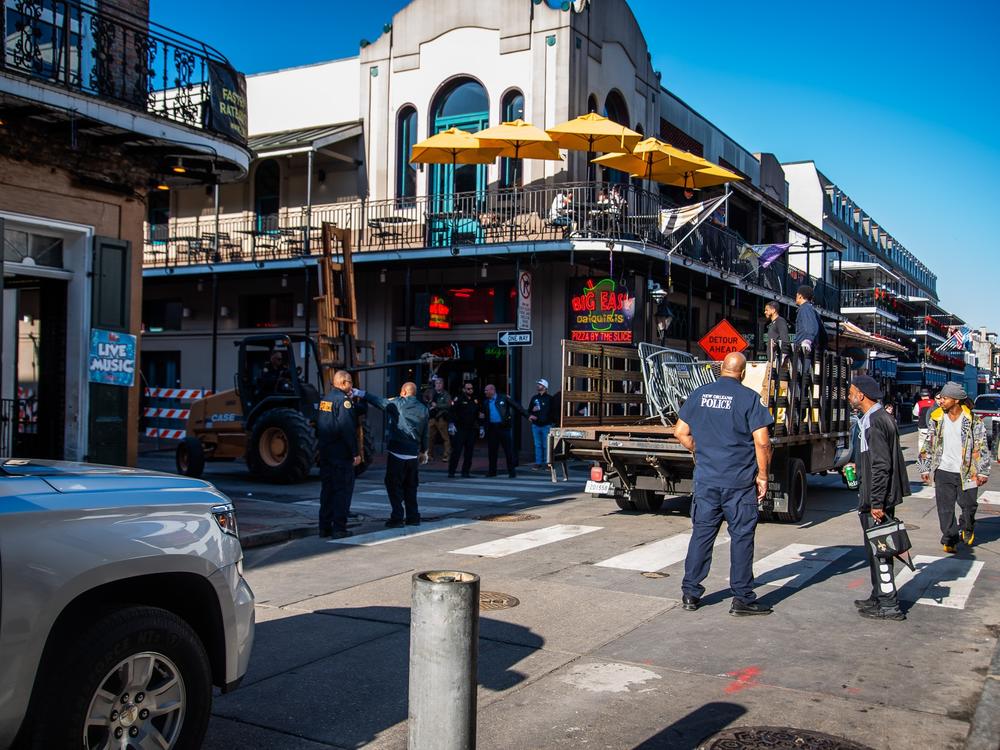 Law enforcement officers watch as barricades are collected with a forklift from Bourbon Street after its reopening.