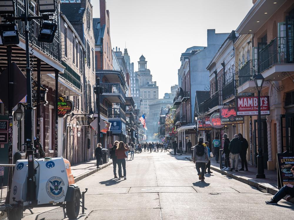 People walk down the re-opened Bourbon Street after New Orleans Police barricades are moved out of the way.⁠