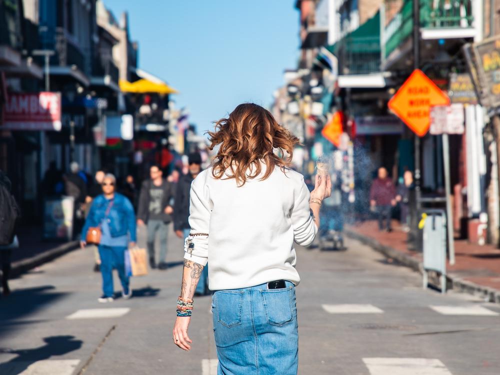 A woman walks down Bourbon Street while burning sage to cleanse the area following the attack.