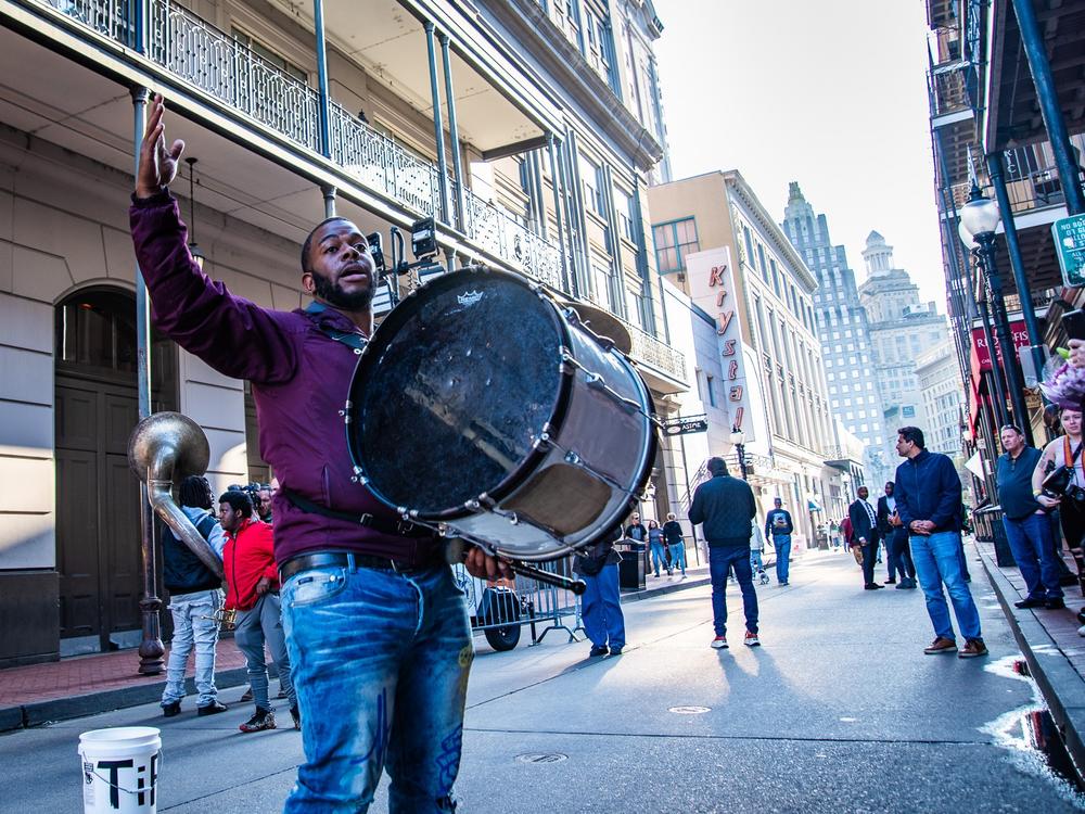 A brass band plays on the corner of Canal and Bourbon streets to a large crowd.