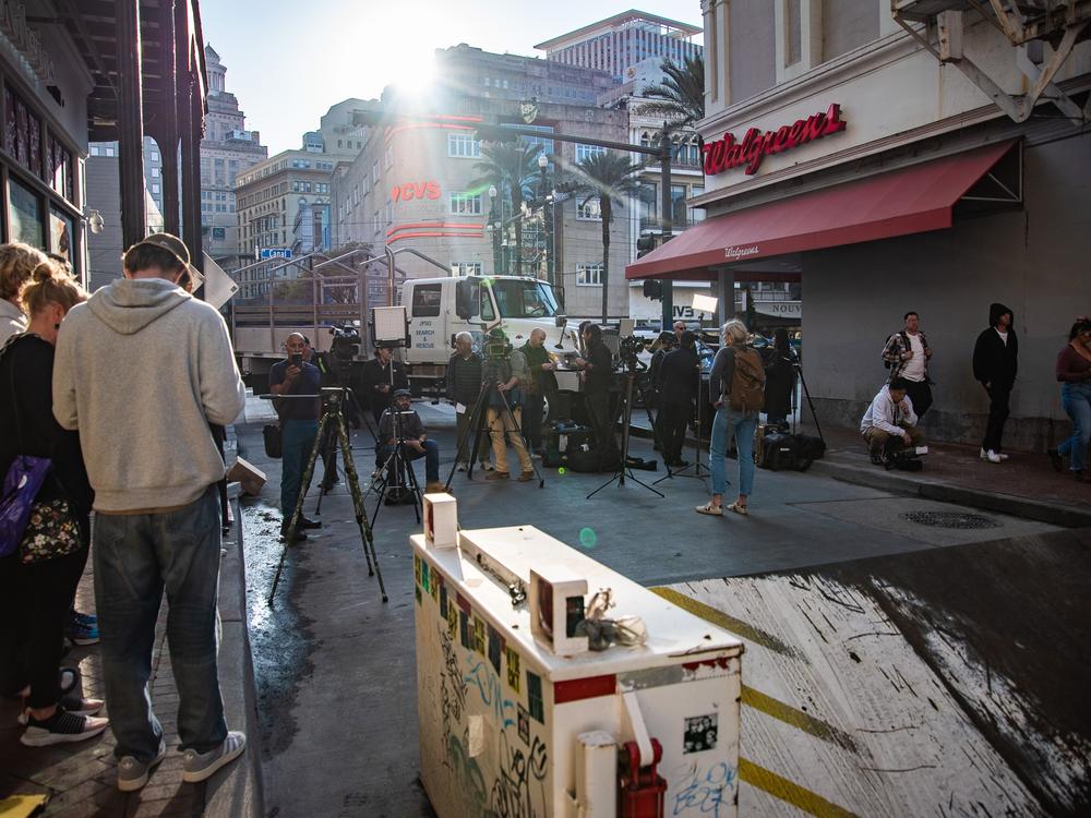 The sun sets over the corner of Canal and Bourbon streets in New Orleans, still blockaded by law enforcement. Local and national media crews set their cameras up in hopes of getting interviews with officials and passersby. ⁠