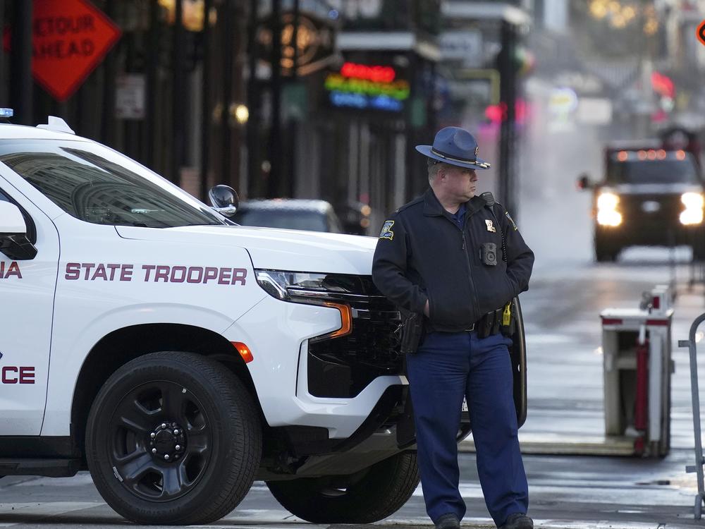 A state trooper stands by New Orleans' Canal and Bourbon streets on Thursday, the day after a truck slammed into a crowd on Bourbon Street, killing at least 14 people.