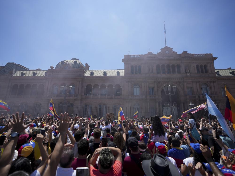 People watch Venezuela's opposition leader Edmundo Gonzalez Urrutia and Argentine President Javier Milei wave to supporters from the government house balcony in Buenos Aires, Argentina, Saturday, Jan. 4, 2025.