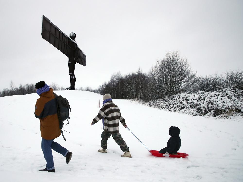 A lady is seen pulling her child along on a sledge as they admire Anthony Gormley's sculpture, the Angel of the North, which is surrounded by heavy snow in Gateshead, North East England, as the severe weather continues across England, on Sunday.