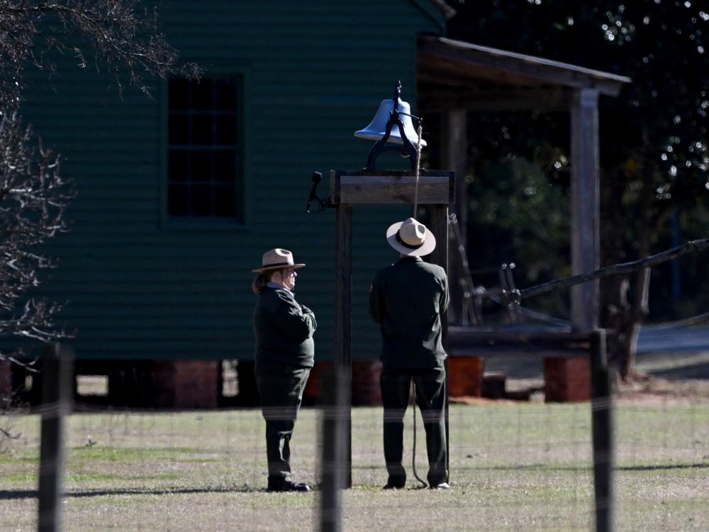 Karen Barry and Randy Dillard, the longest serving NPS Plains staffers, ring the farm bell 39 times as the hearse containing the casket of former President Jimmy Carter pauses at the Jimmy Carter Boyhood Farm in Archery, Ga.