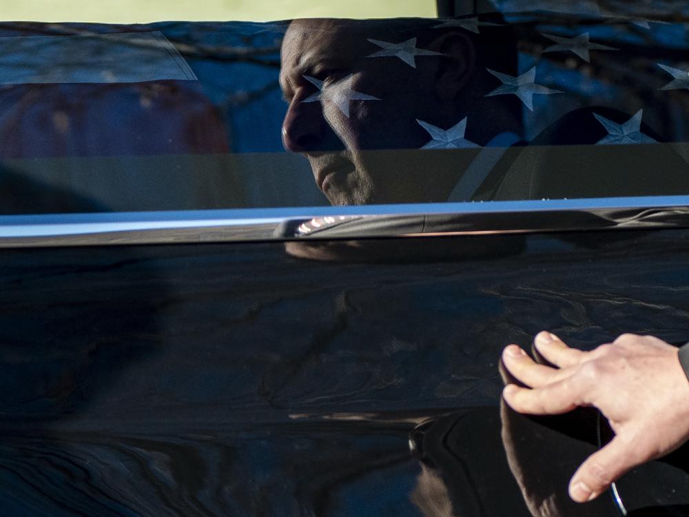 A U.S. Secret Service agent assigned to the Carter detail places his hand on the hearse containing the casket of former President Jimmy Carter, at Phoebe Sumter Medical Center.