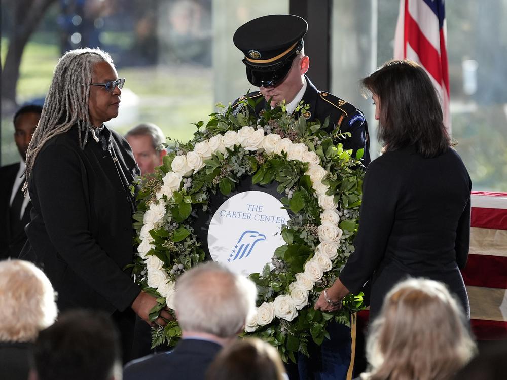 Meredith Evans, director of the Jimmy Cater Presidential Library and Museum, left, and Paige Alexander, CEO of The Carter Center place a wreath during a service for former President Jimmy Carter at the Jimmy Carter Presidential Library and Museum.