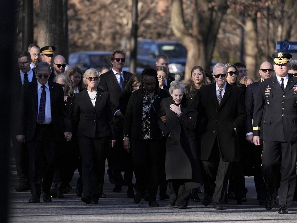Jack Carter, second right, the son of former President Jimmy Carter, walks with family and escorts as his father's casket arrives at the Jimmy Carter Presidential Library and Museum, where Carter's casket will lie in repose.