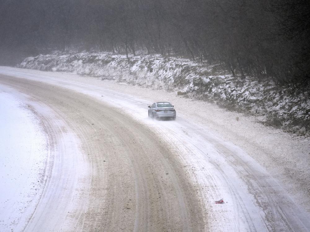 A car slowly navigates a snow-covered interstate Sunday, January 5, 2025, in St. Louis, Missouri. (AP Photo/Jeff Roberson)