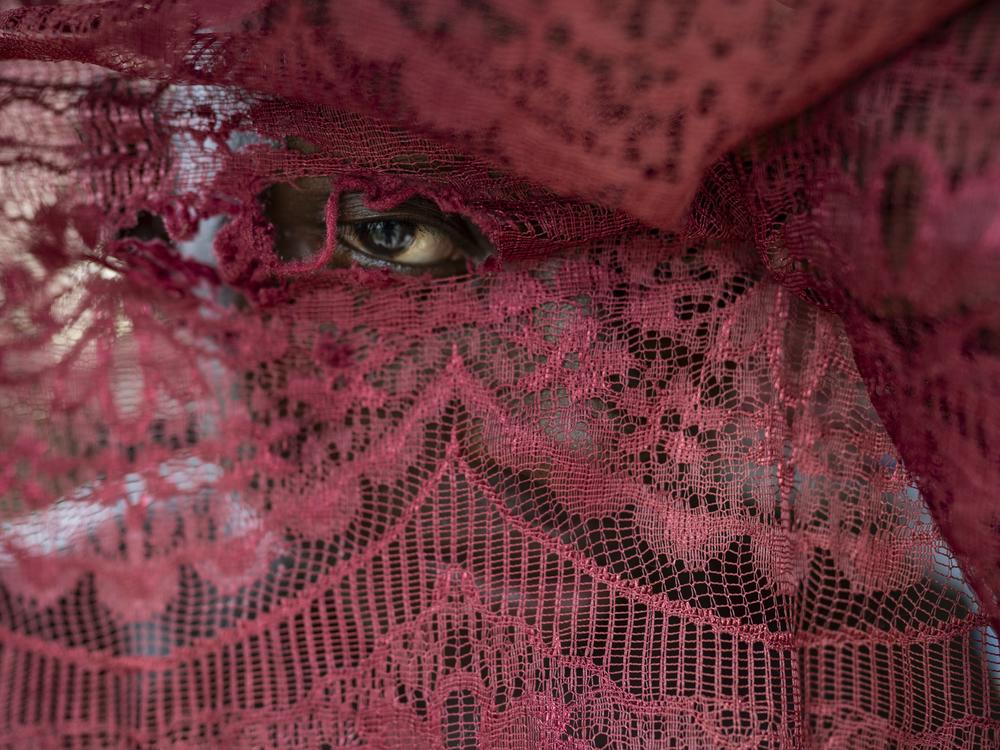 Camilo Garcia peeks through a curtain of his house on the morning of March 29, 2024, in the town of Juntas, Buenaventura, Colombia. The community gathers during Holy Week to celebrate the Manacillos festival, an ancestral ritual originating in the upper part of the Yurumangui River.