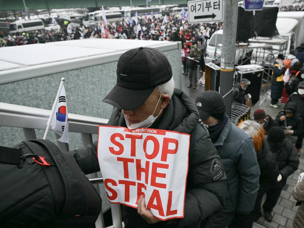 A supporter of impeached South Korean President Yoon Suk Yeol holds a placard reading 