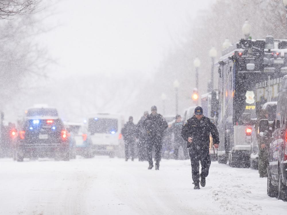 Police officers and vehicles line First Street NE in the snow outside the U.S. Capitol as security tightens in advance of the Joint Session of Congress to count the electoral votes.